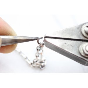 工具で丸カン部分の片方を手前、もう片方を奥側に開いて下さい。